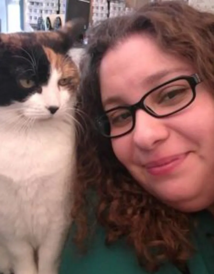 Priscilla Figueroa's staff photo from Shinnecock Animal Hospital where she is posing next to a calico cat that's on her desk.